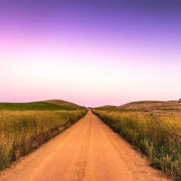 A straight road through some hills at sunset