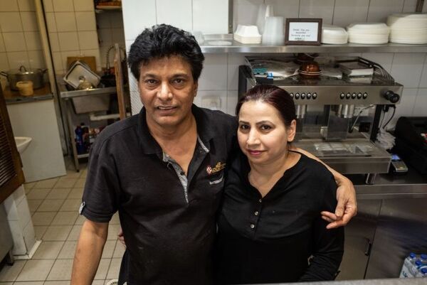 A couple standing in a restaurant kitchen. 