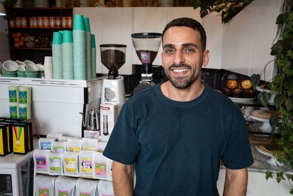 A youngish man smiling in a cafe. 