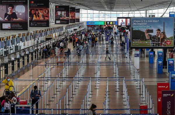 An airport in Santiago is seen with relatively few travellers near check-in desks.