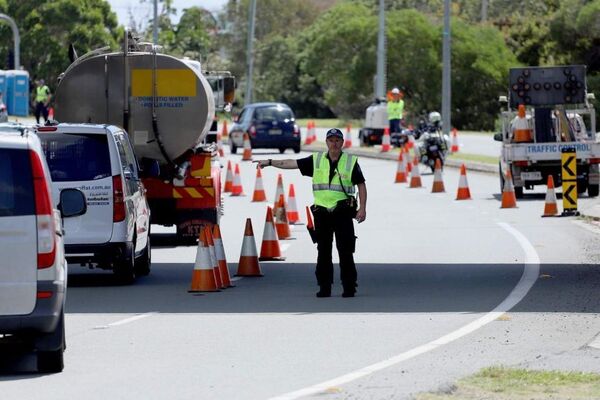 A police officer at a checkpoint directs motorists lined up at Queensland-NSW border at Coolangatta.