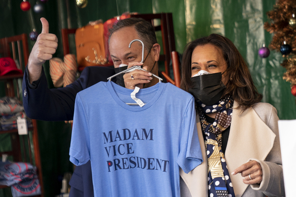 Kamala Harris smiles while holding up a tshirt with Madam Vice President