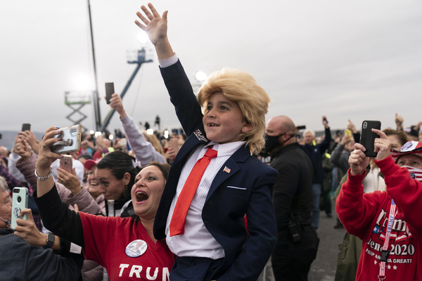 A child in a Donald Trump costume waves 