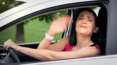 A woman waves and kisses as she drives away in a car