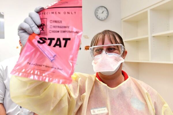 A nurse wearing a face mask holds up needles inside a bag in a fever clinic.
