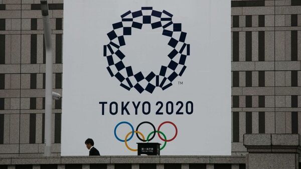 A man walks past a large banner promoting the Tokyo 2020 Olympics.