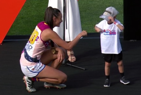 A Brisbane Lions AFLW player gives a fist pump to a young child who awarded her a premiership medal.