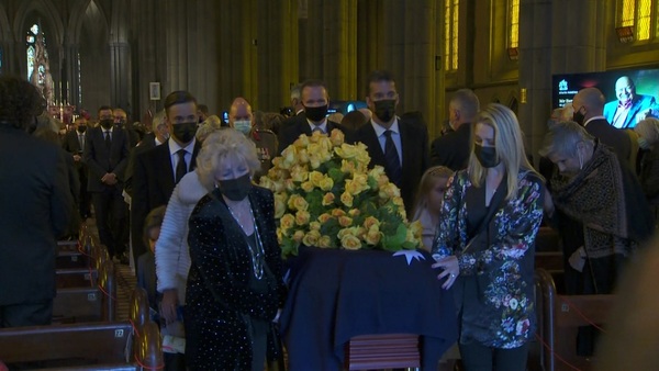 Patti Newton walks beside a yellow-rose adorned coffin out of St Patrick's cathedral.