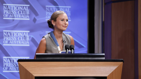 Grace Tame standing at the podium at the National Press Club