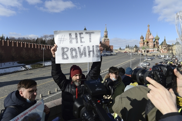 A man holds up a sign in Russian.