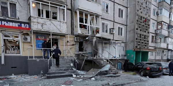 The front of a building is damaged, the ground in front littered with debris