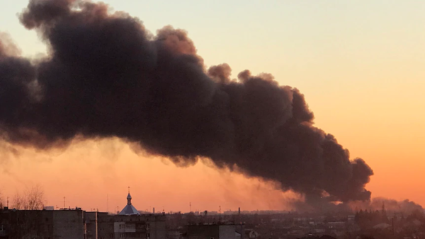A huge pillar of smoke rises into the sunset sky over Liviv