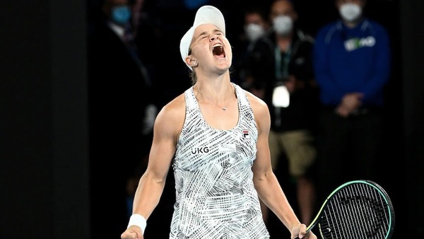Ash Barty, wearing a Fila tennis dress with UKG on the chest, shouts as she clenches both fists.