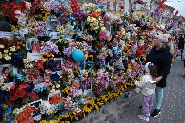 A woman and a child admire the memorial wall, which stretches long past the edge of the frame of the picture