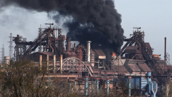 a large factory, black smoke billows from the centre